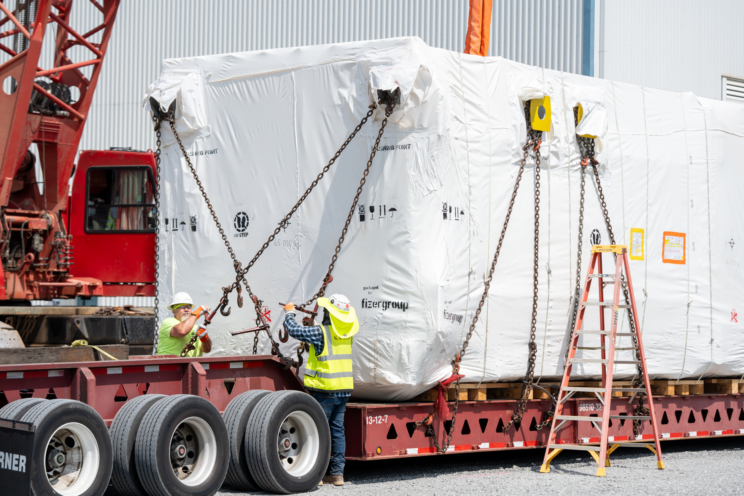 crews unpacking massive condenser pieces and prepare for assembly